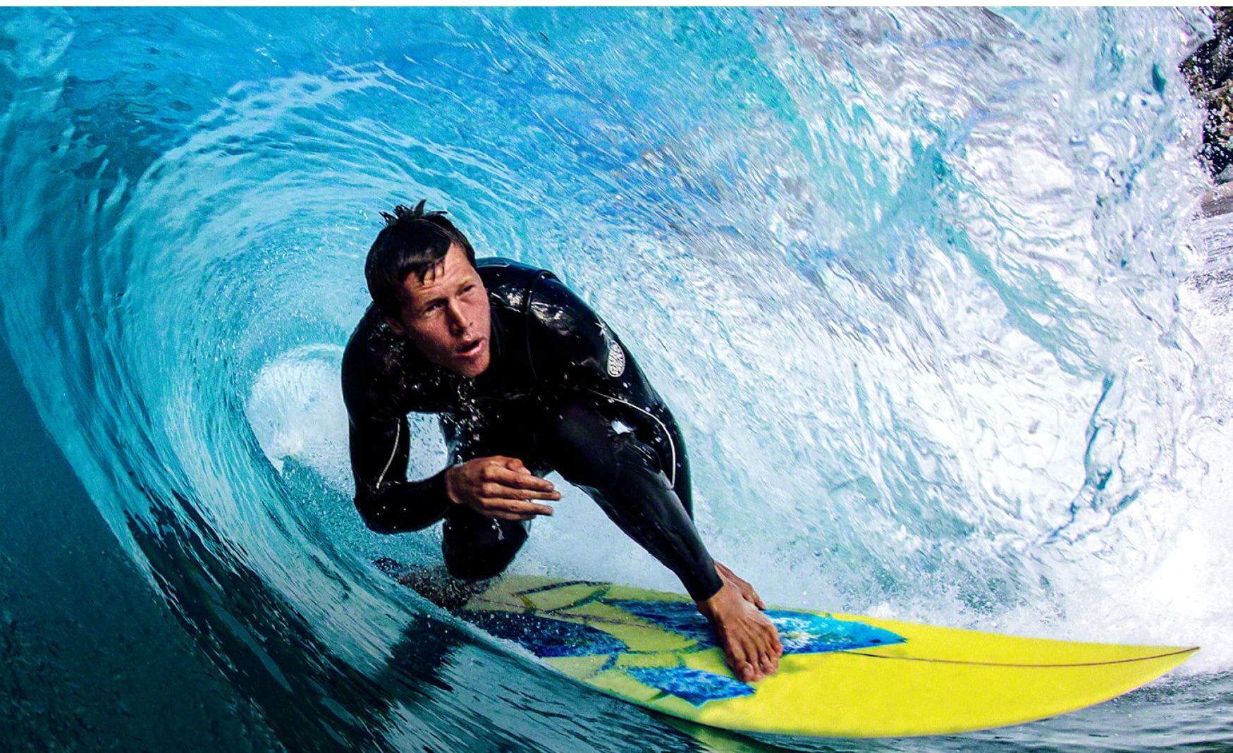 a man in a wetsuit is riding a wave on a surfboard showing blur-free picture quality on a sony mini led tv