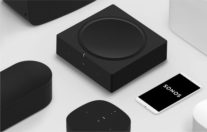a sonos amp is sitting next to a phone and can be controlled by the phone