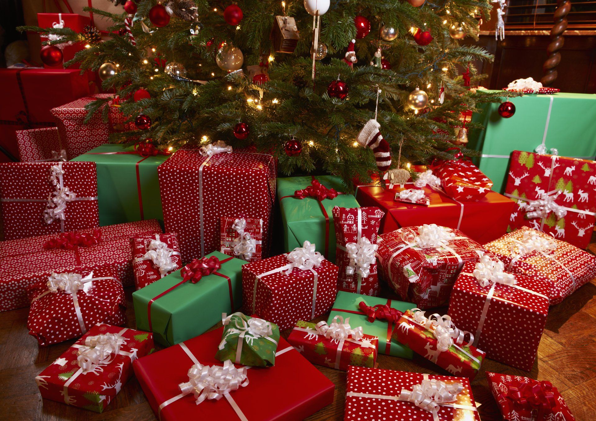 a Christmas tree is surrounded by electronics presents wrapped in red and green