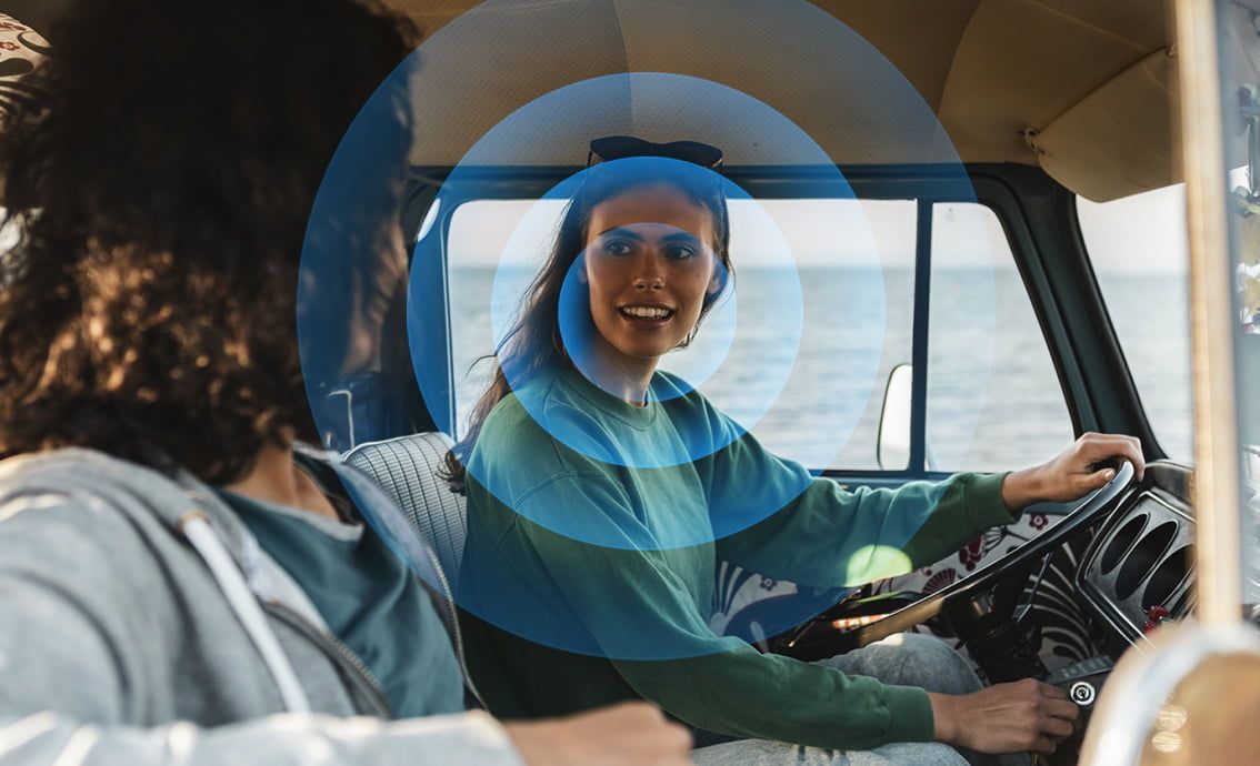 a woman driving a car with a blue circle around her mouth emphasizing clear voice audio from a sony tv