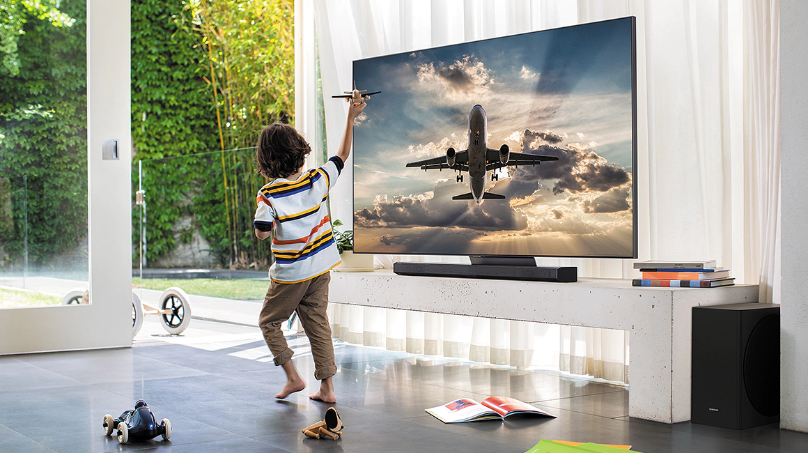 a young boy is playing with a toy airplane in front of a flat screen tv.  4K TV sales by fisher electronics in northern ohio