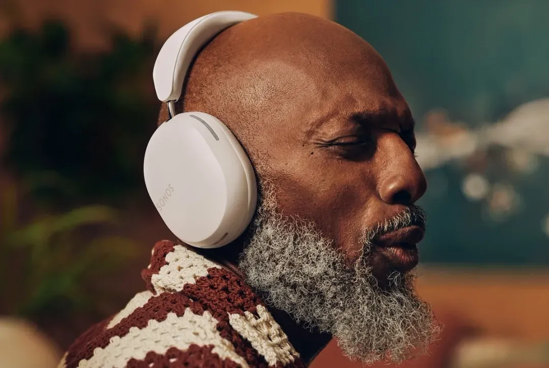 A bald man with a beard is wearing sonos headphones.