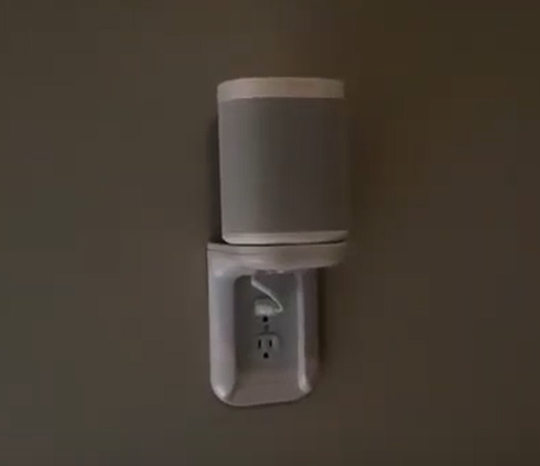 a speaker is mounted to a wall next to an electrical outlet .