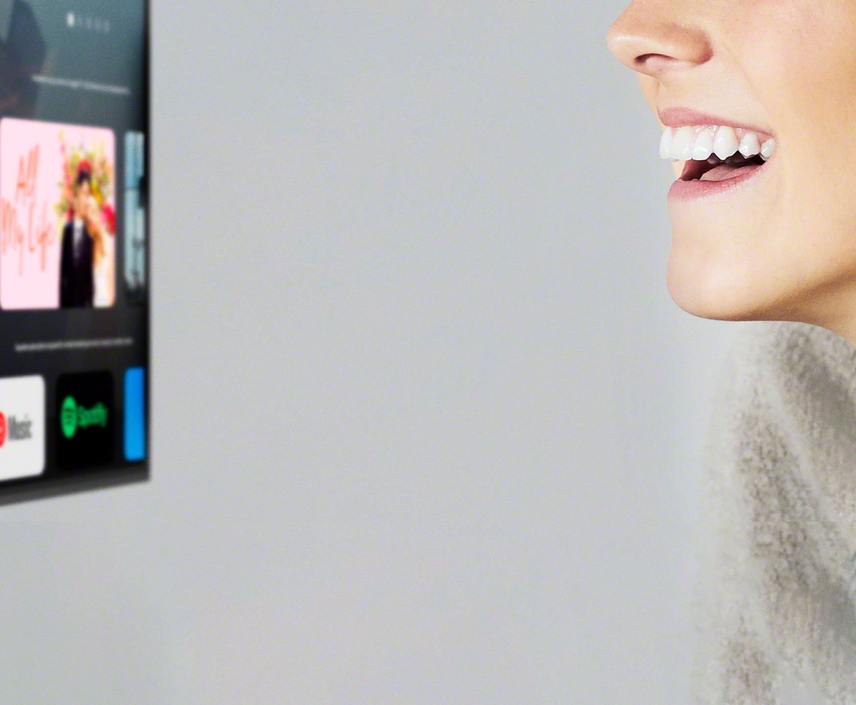 a woman 's mouth talks to a sony tv that shows youtube and spotify