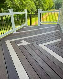 Deck with geometric pattern using gray and white composite decking. White railing surrounds.