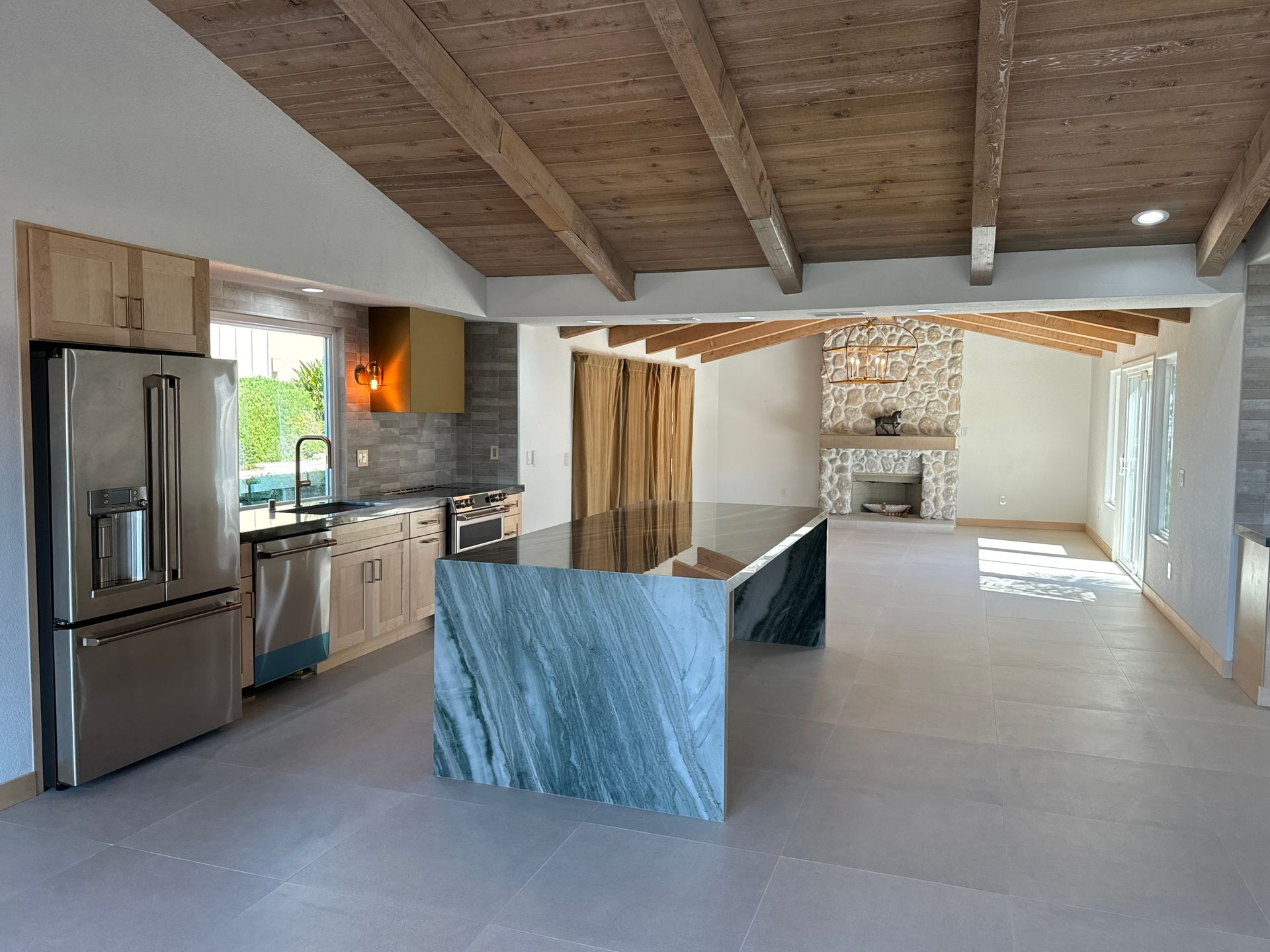Modern kitchen with a large island, stainless steel appliances, and a stone fireplace.