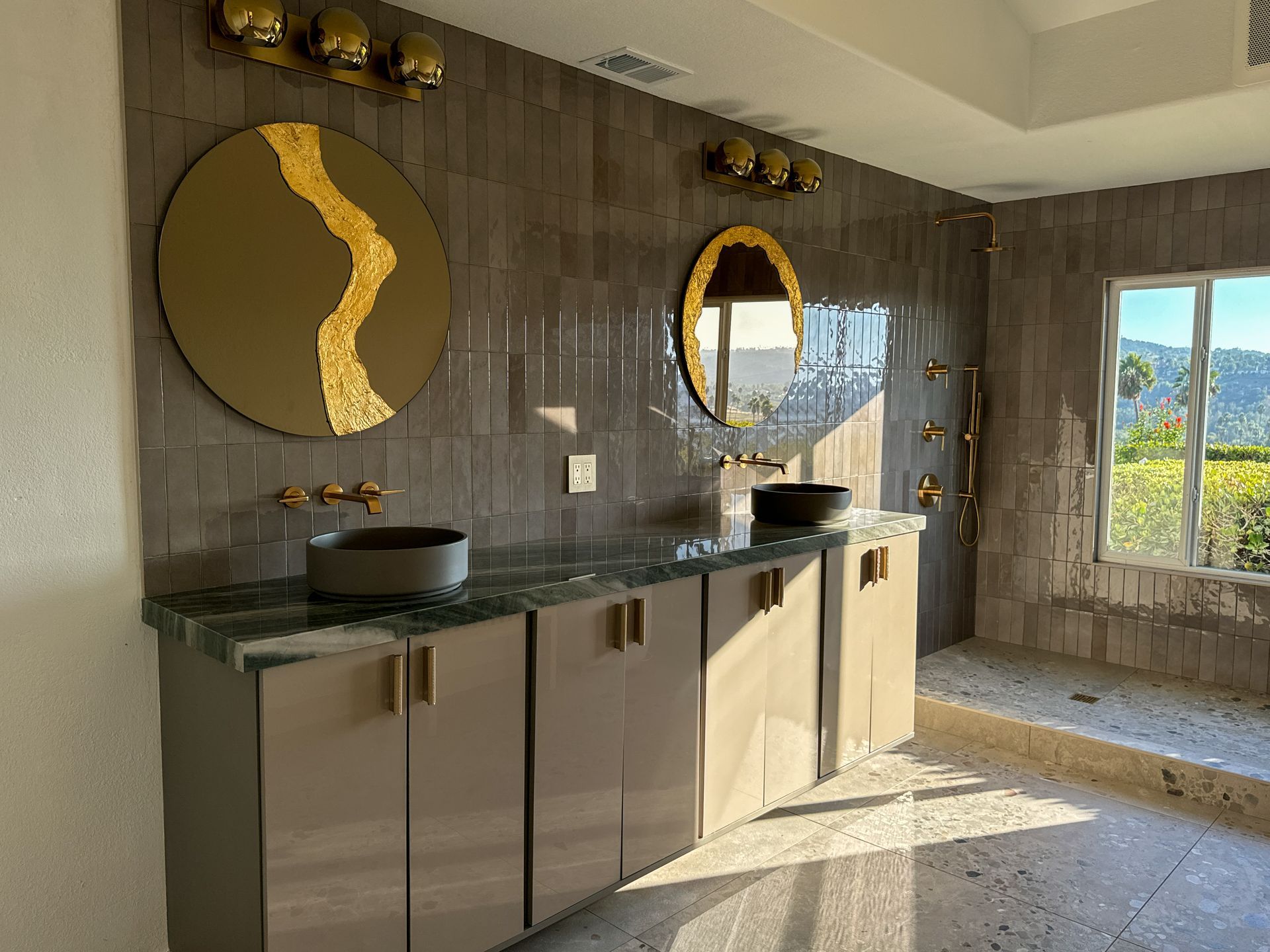 Modern bathroom with a double vanity, round mirrors, and gold accents.