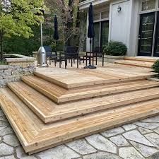 Wooden multi-level deck with outdoor seating, near a house with black umbrellas.