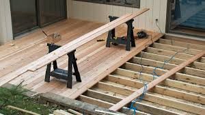 Deck construction: wood planks being laid over joists, saw horses supporting lumber.