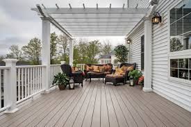 Deck with pergola, white railing, and seating area by a house.