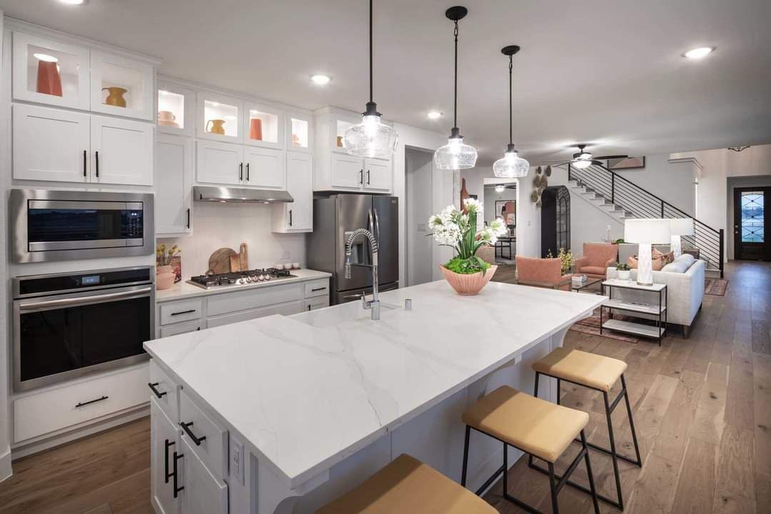 Modern kitchen with white cabinets, large island, and stainless steel appliances.