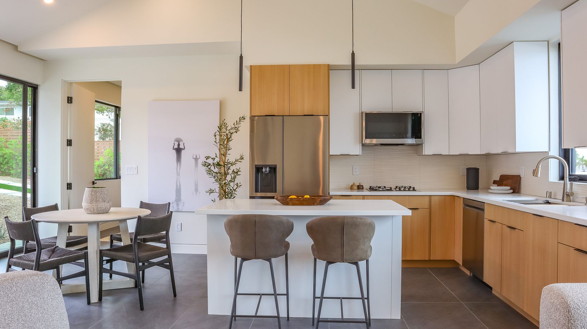 Modern kitchen with light wood and white cabinetry, a breakfast bar, and a dining area.