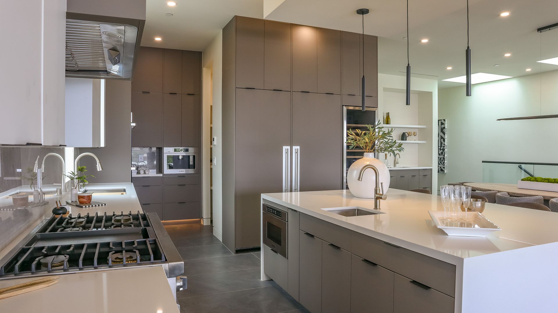 Modern kitchen with gray cabinets, island, and stainless steel appliances.