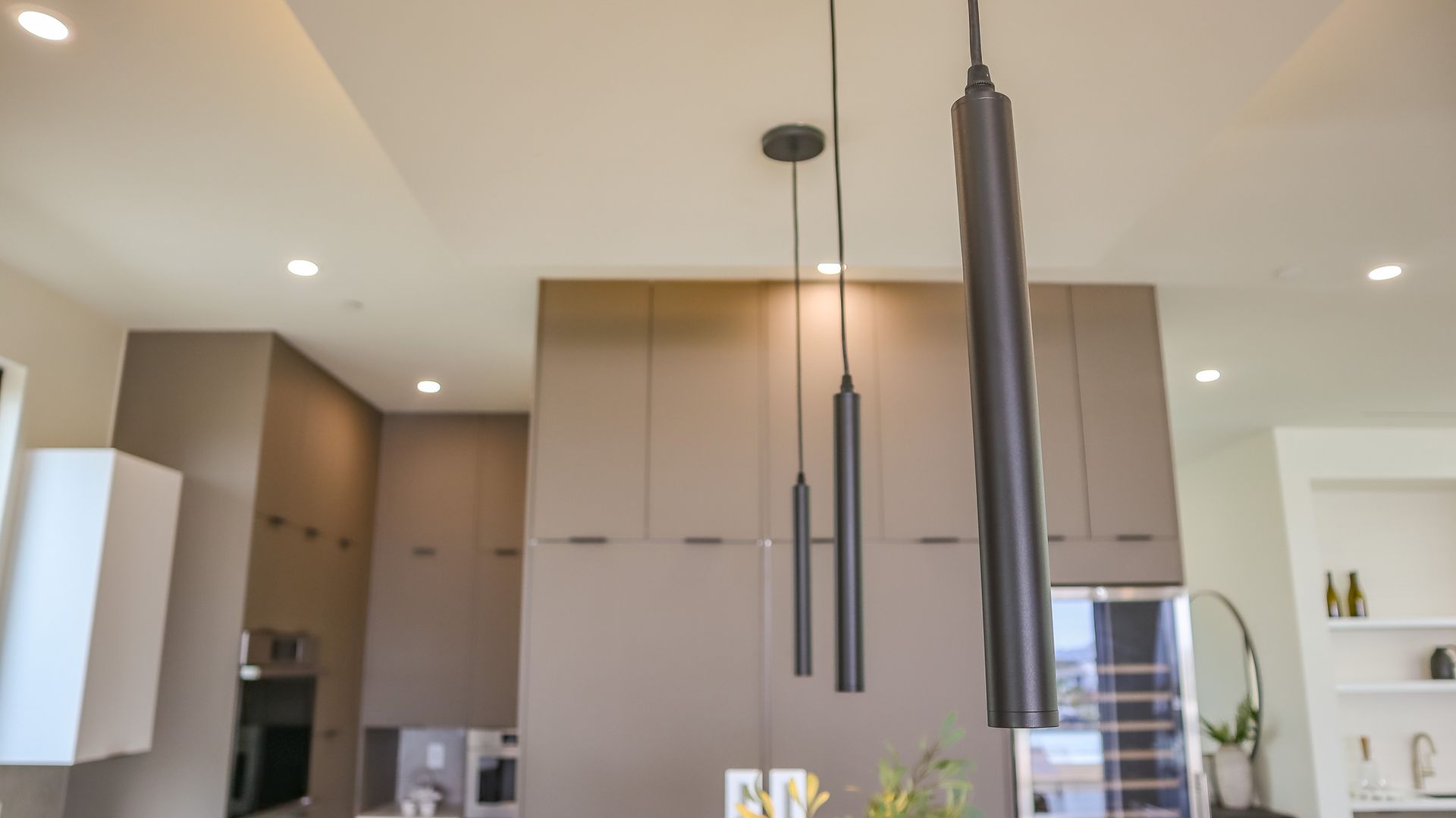 Kitchen with brown cabinets, black pendant lights, and recessed lighting.