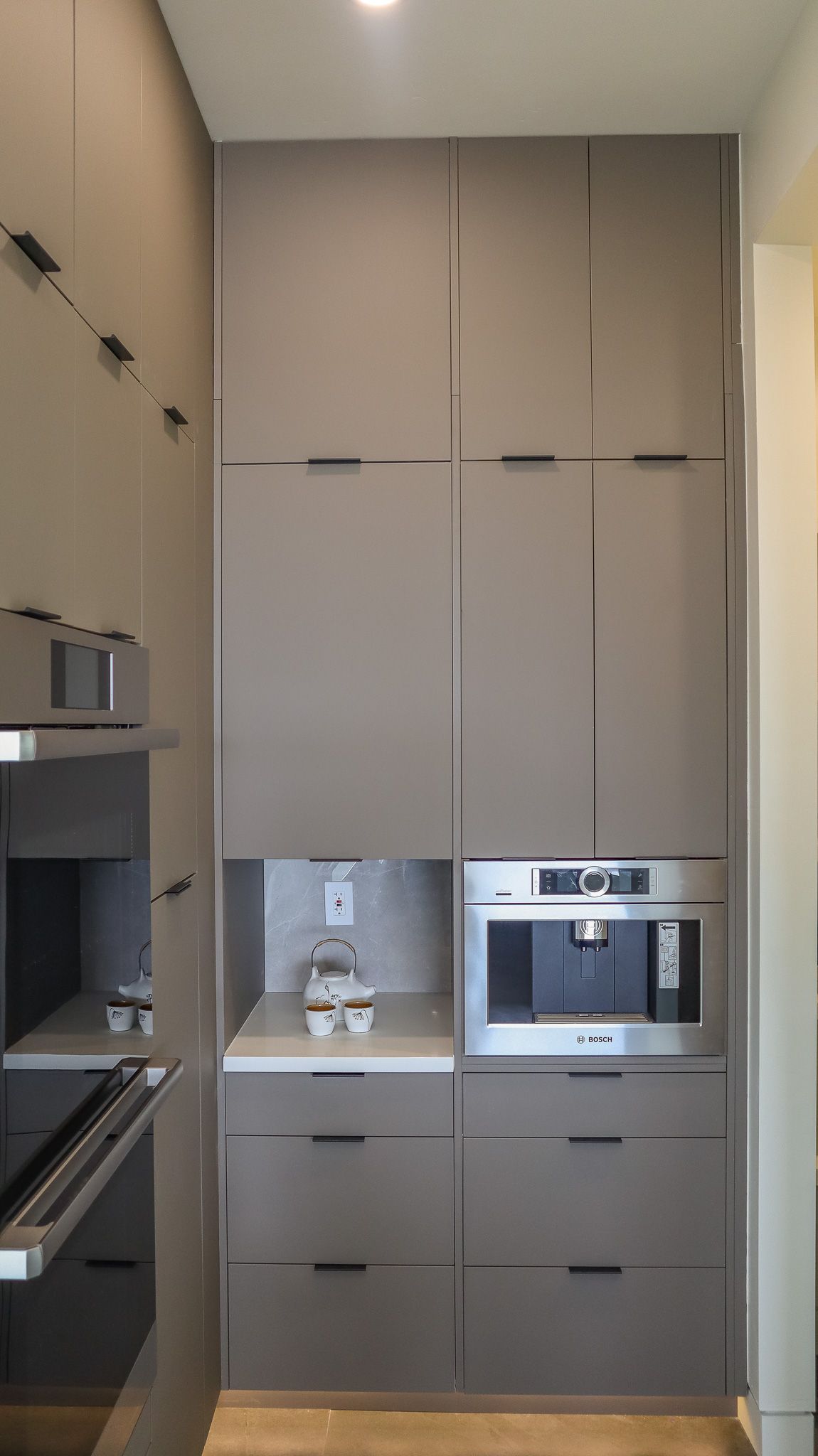 Gray built-in kitchen cabinets with coffee maker and microwave, vertical design.