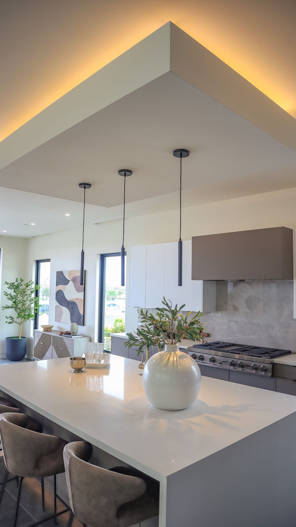 Modern kitchen with island, pendant lights, and decorative vase. Recessed ceiling lighting.