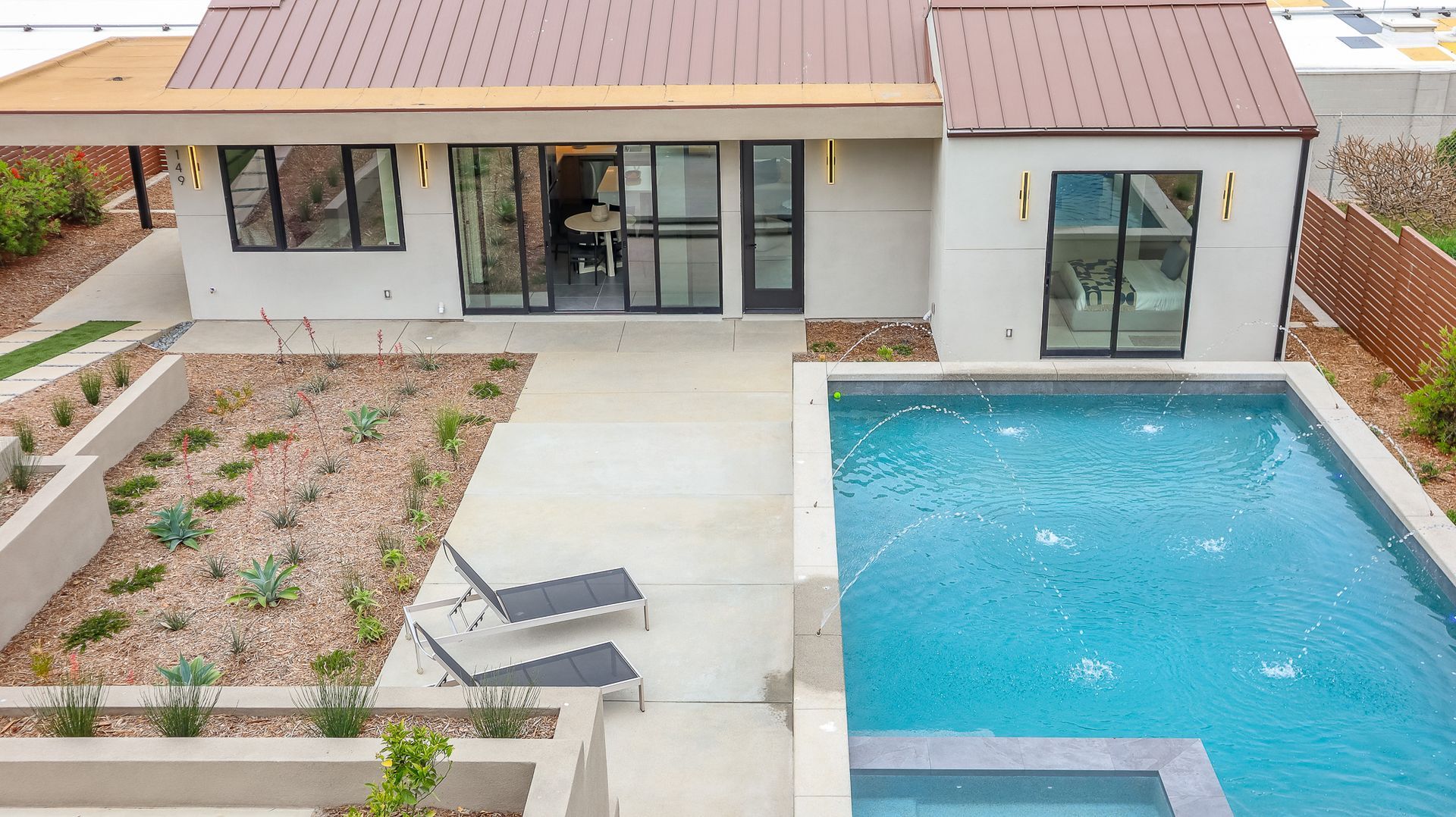 Exterior view of a modern house with pool and landscaping. The roof is copper colored.
