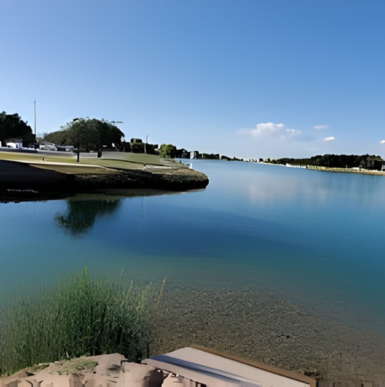 Scenic lakeside park with grassy picnic areas, walking paths, and calm water at Lake Carlsbad Beach Park.