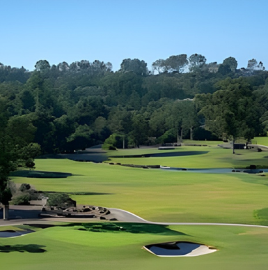 Lush green fairways and manicured landscaping with elegant clubhouse and towering trees at Rancho Santa Fe Golf Club
