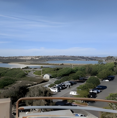 Sandy beach with ocean waves, campers on the bluffs, and a clear coastal view at South Carlsbad State Beach.
