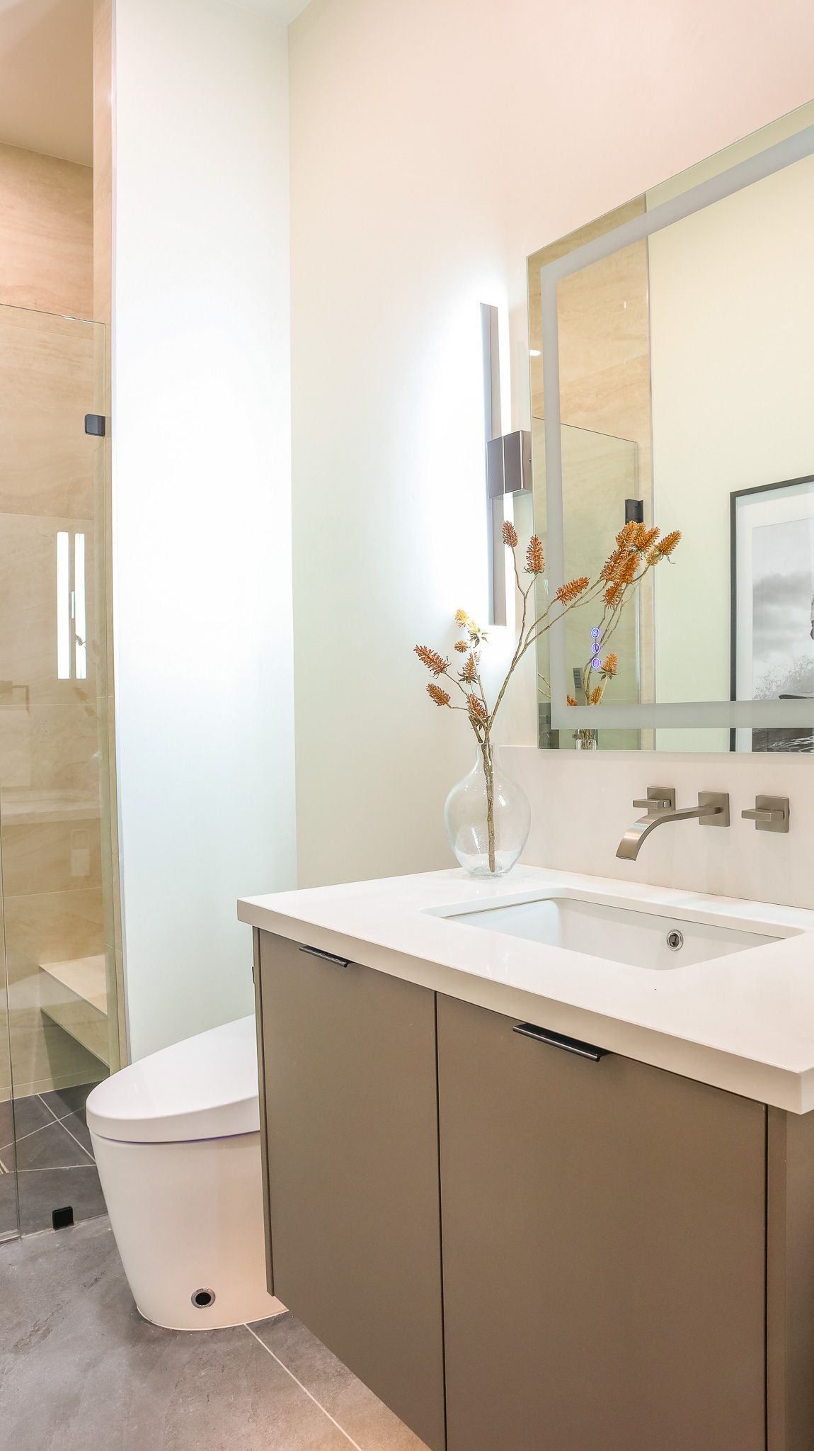 Modern bathroom with beige vanity, white countertop, and glass shower.