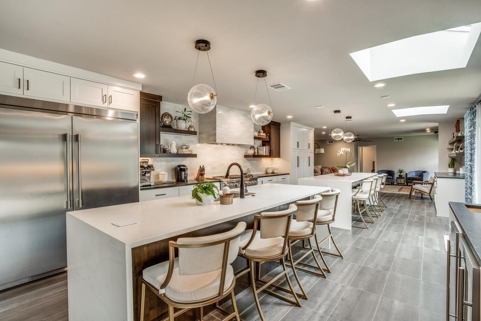 Modern kitchen with a large island, stainless steel appliances, and white cabinets.