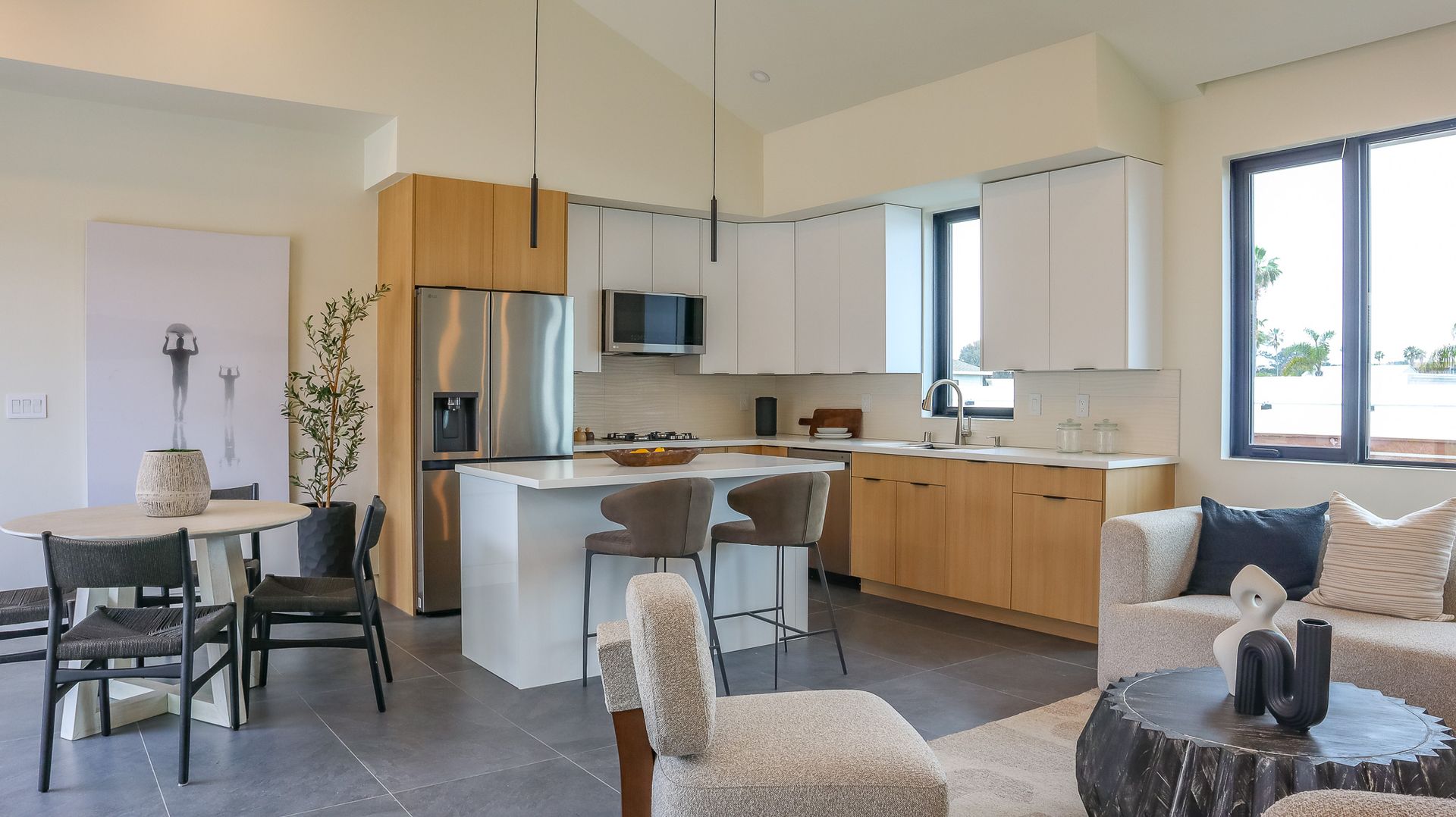 Open-concept kitchen and living area with white and wood cabinets, stainless steel appliances, and a round dining table.