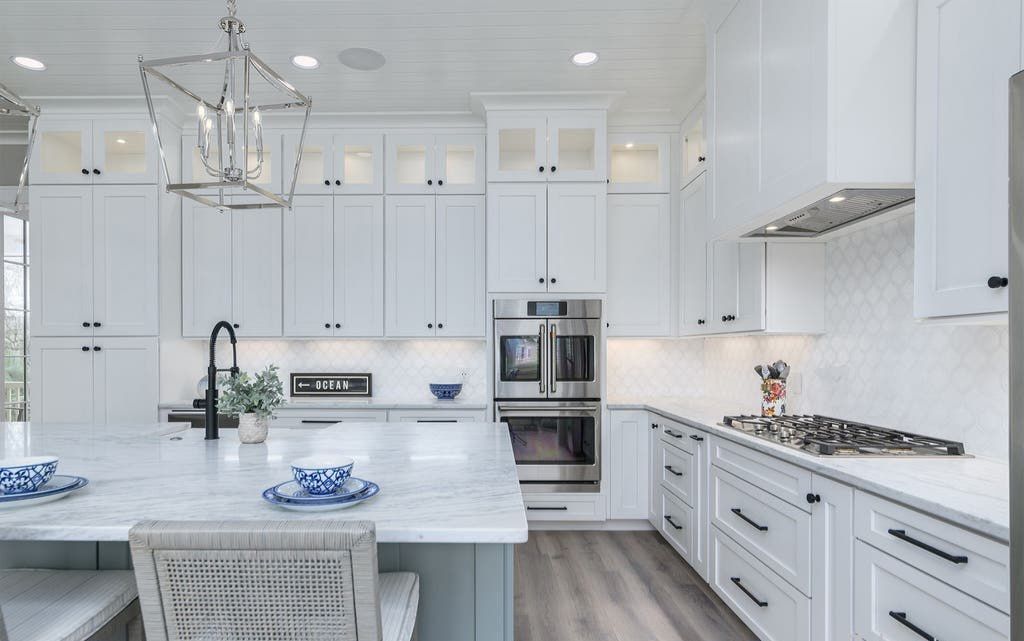 White kitchen with island, cabinets, stainless steel appliances, and gray countertops.