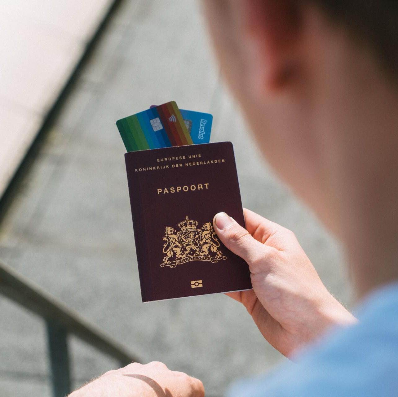 Una persona sostiene un pasaporte holandés de color rojo oscuro 