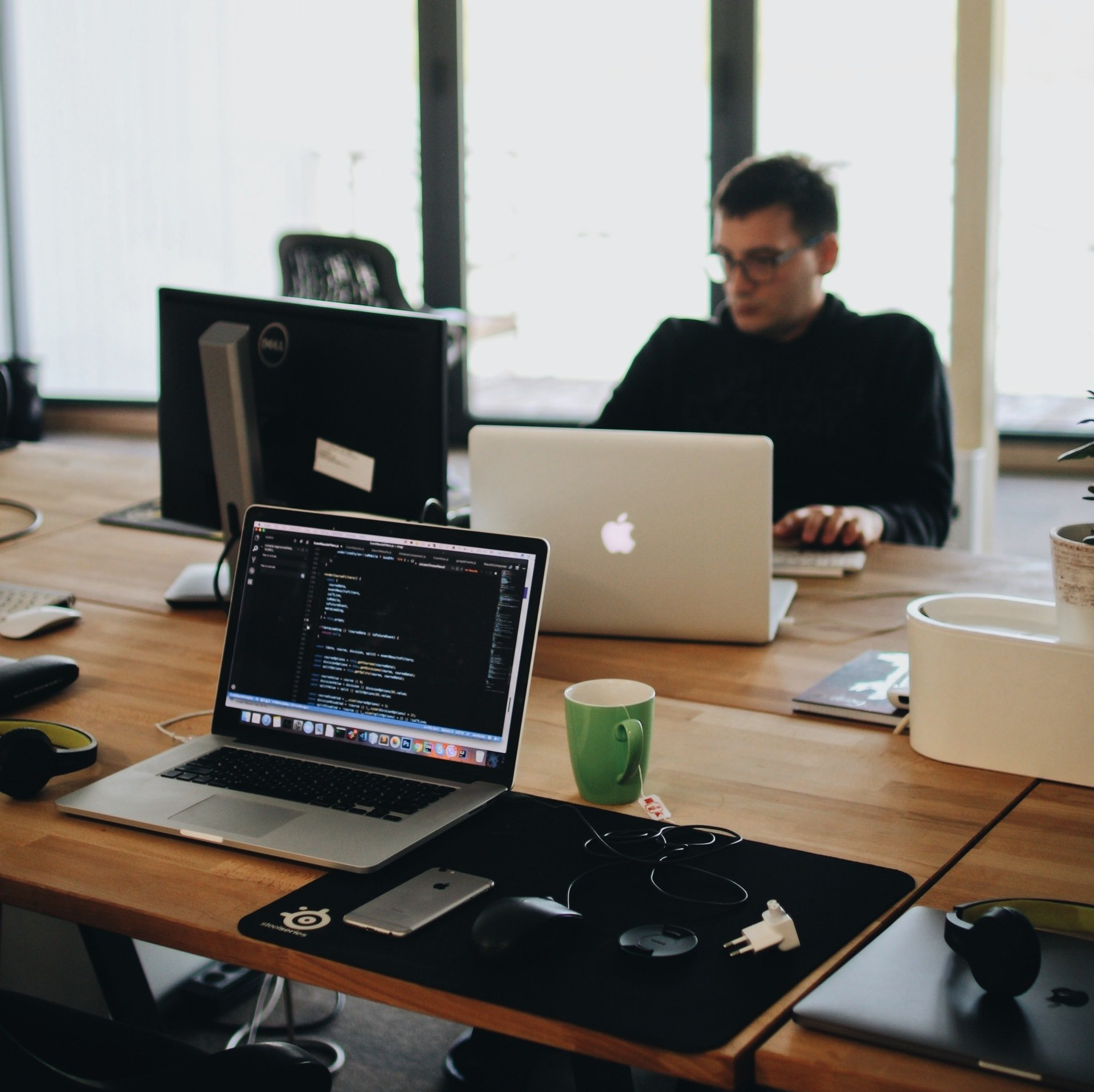 Una persona trabaja en un escritorio con dos computadoras portátiles