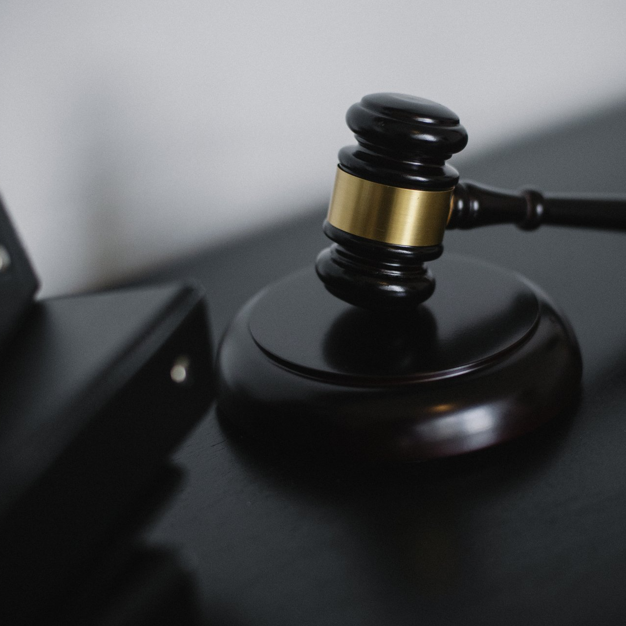 Un mazo de juez de madera descansa sobre su bloque circular que resuena en una superficie oscura.