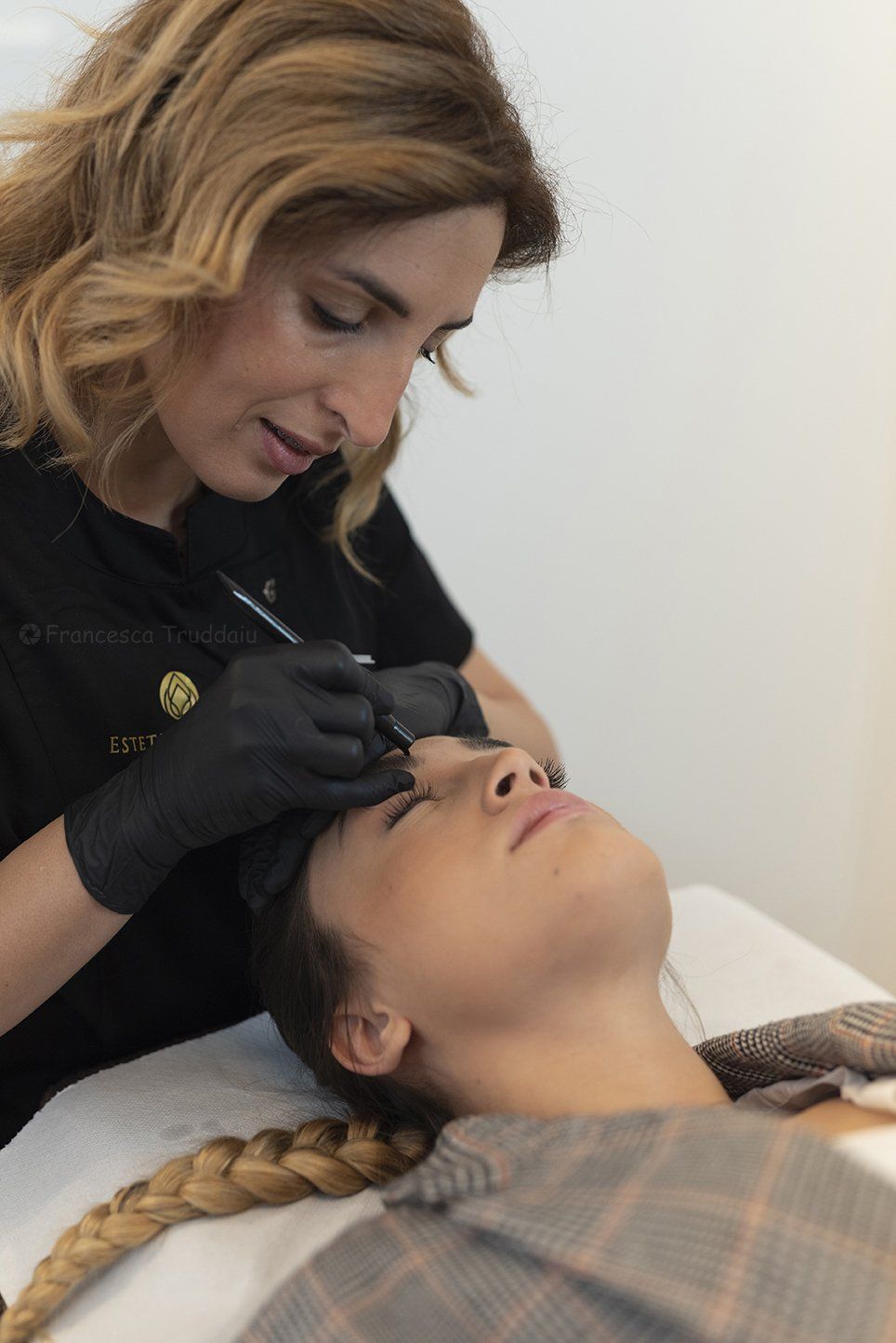 Donna che si sottopone a una procedura per le sopracciglia; professionista al lavoro con guanti neri, primo piano.