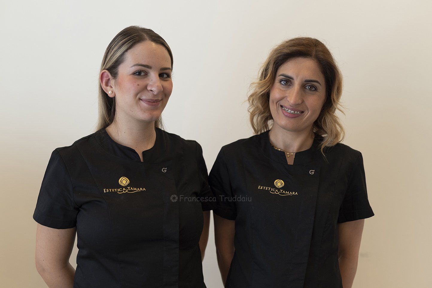 Due donne in uniforme nera che sorridono.