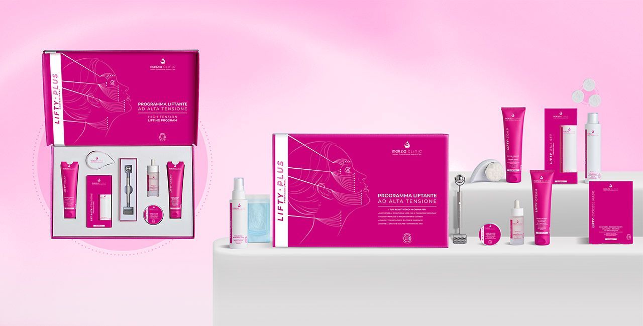 Set di prodotti per la cura della pelle rosa su una superficie bianca, con uno sfondo rosa.