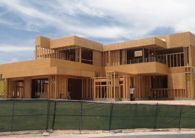 A large house is being built with a green fence in front of it