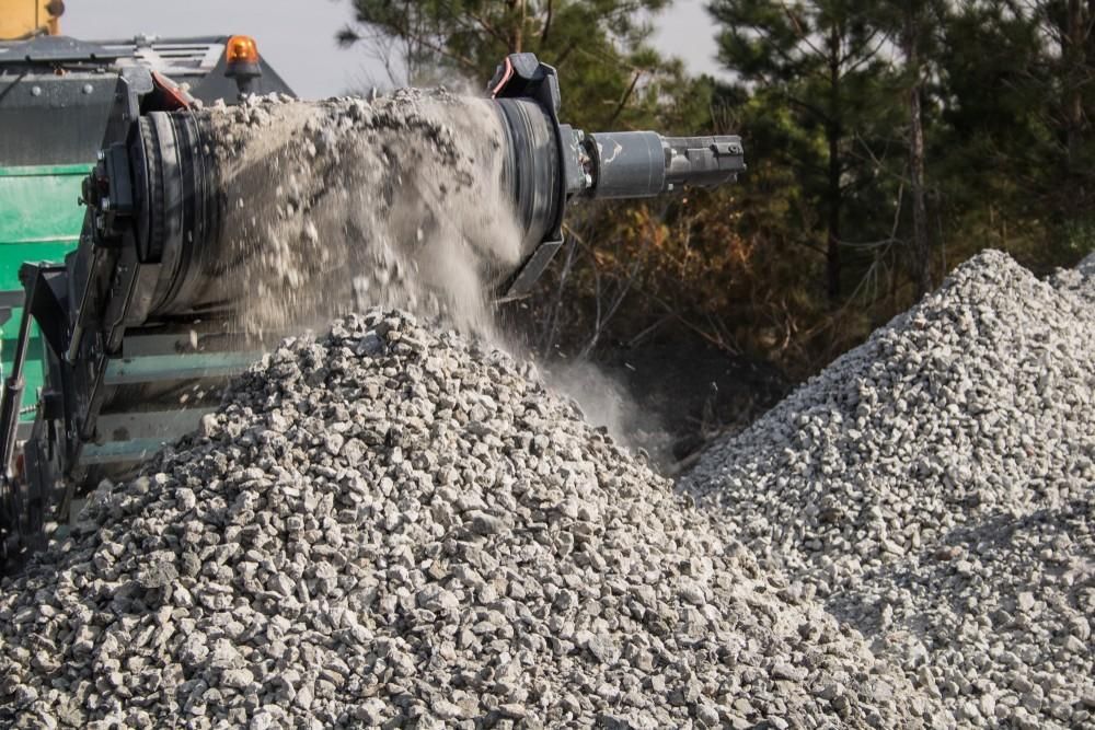 A Machine Crushing Rocks, Creating a Pile of Gravel — Coastcrete Concrete Specialist in Raymond Terrace, NSW