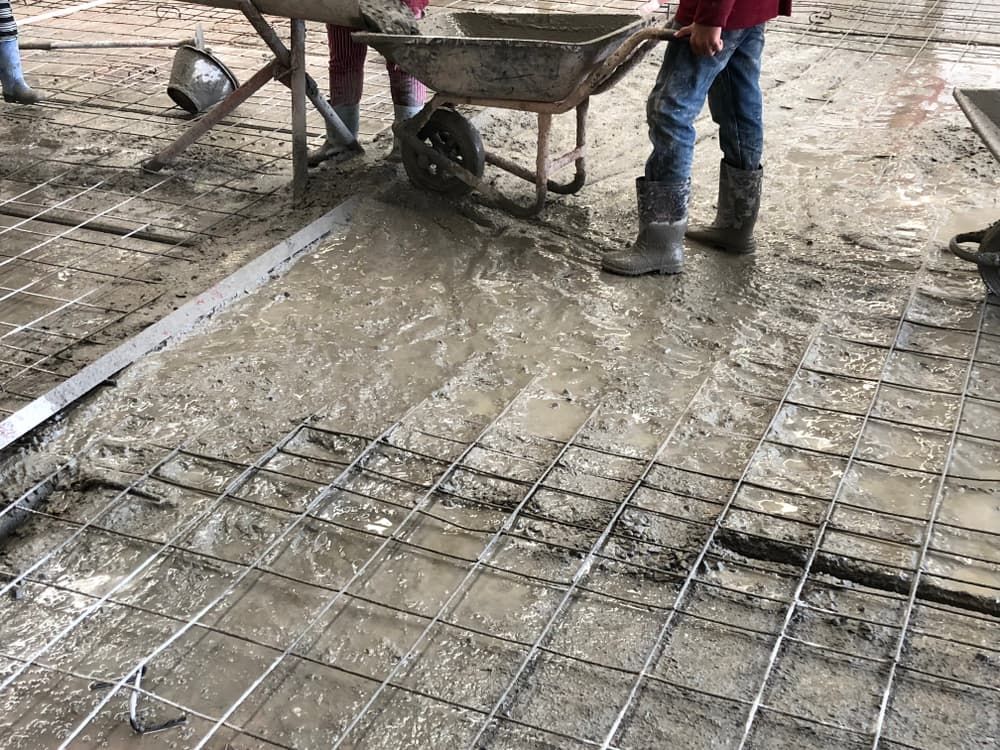 Construction Workers Pouring Concrete Over a Wire Mesh — Coastcrete Concrete Specialist in Taylors Beach, NSW