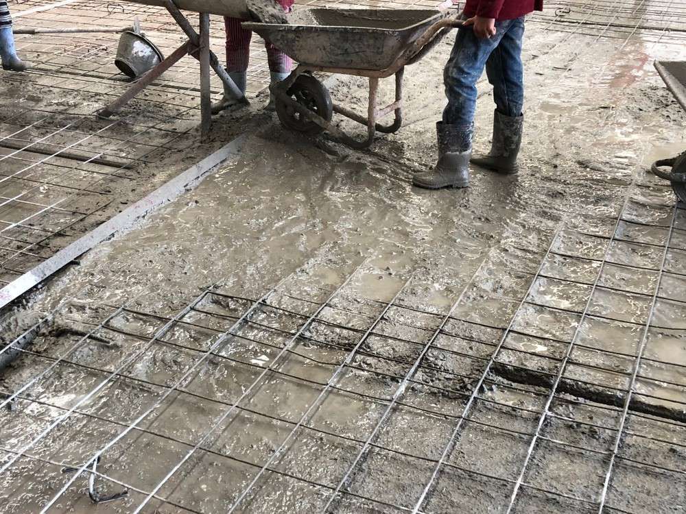 Construction Workers Pouring Wet Concrete Over Steel Reinforcement — Coastcrete Concrete Specialist in Medowie, NSW