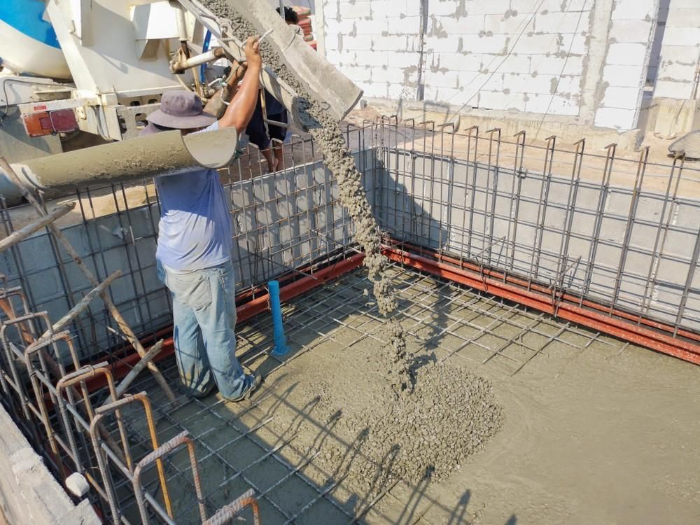 Construction Worker Pouring Concrete Into a Form Lined with Rebar — Coastcrete Concrete Specialist in Medowie, NSW