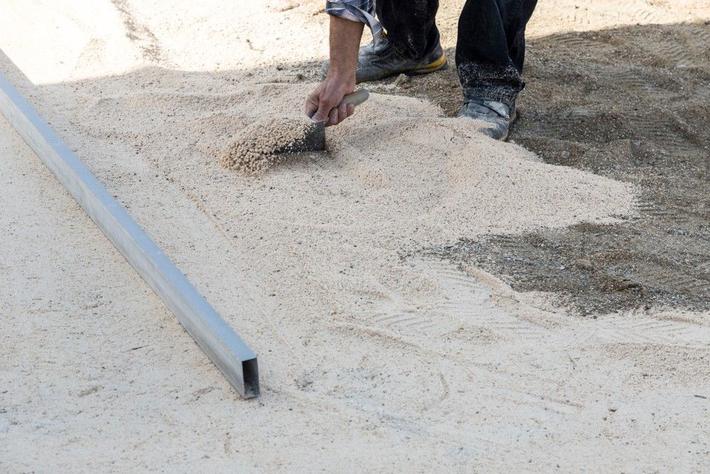 Person Leveling Sand with A Trowel Next to A Metal Beam — Coastcrete Concrete Specialist in Anna Bay, NSW