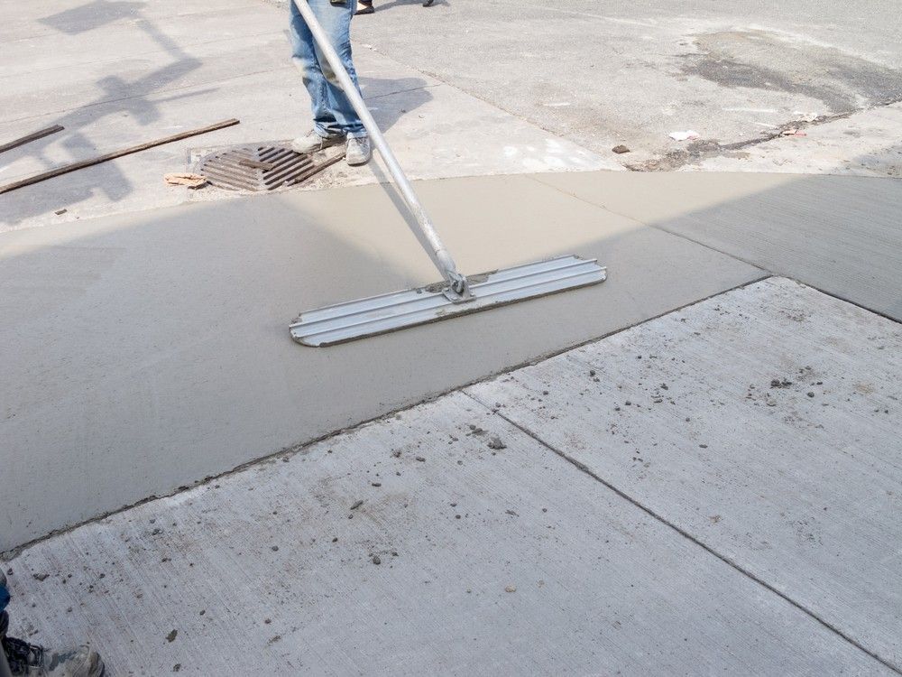 Person Using a Screed to Level Wet Concrete on A Sidewalk — Coastcrete Concrete Specialist in Medowie, NSW