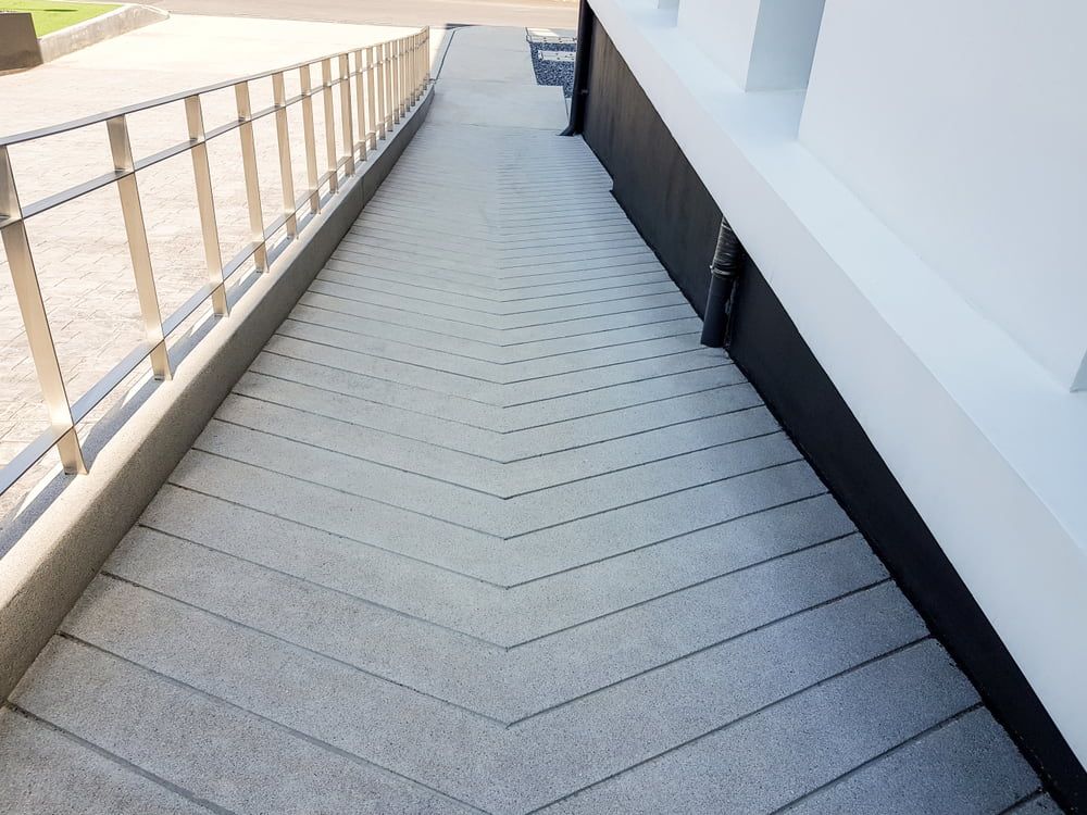 Concrete Ramp with Chevron Grooves Leading to A White Building — Coastcrete Concrete Specialist in Taylors Beach, NSW