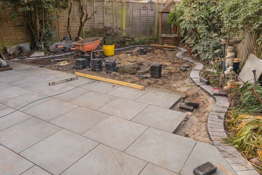 Patio Construction: Gray Stone Tiles Being Laid — Coastcrete Concrete Specialist in Tea Gardens, NSW