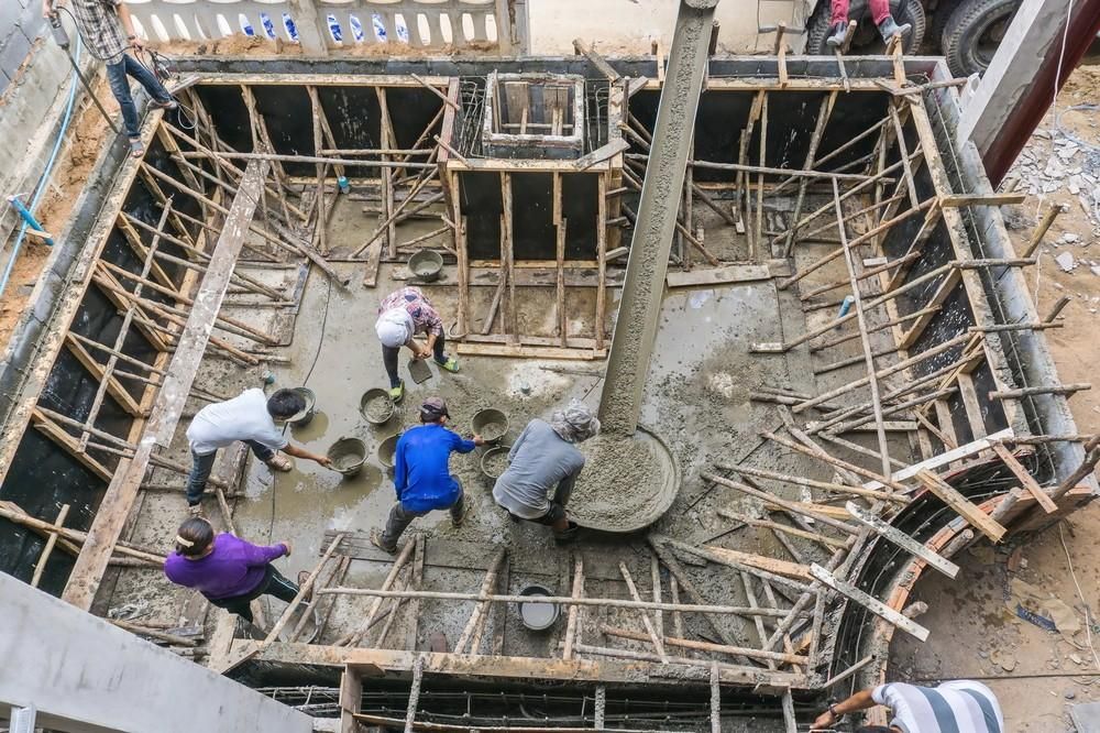 Construction Workers Pouring Concrete Into a Wooden Framework — Coastcrete Concrete Specialist in Medowie, NSW