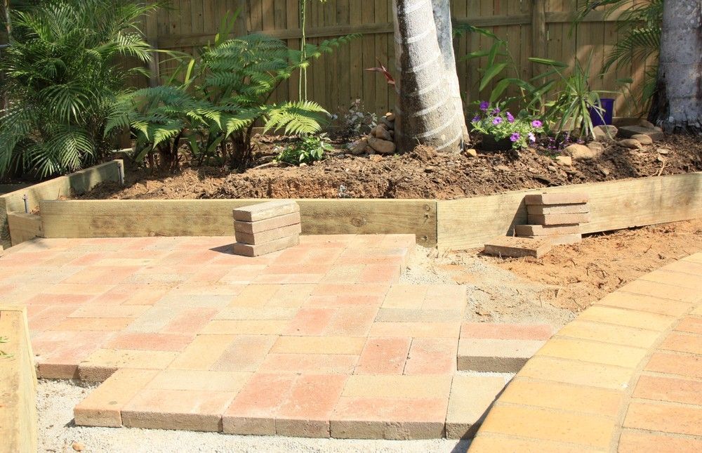 Brick Patio Under Construction Next to A Raised Garden Bed with A Palm Tree — Coastcrete Concrete Specialist in Anna Bay, NSW