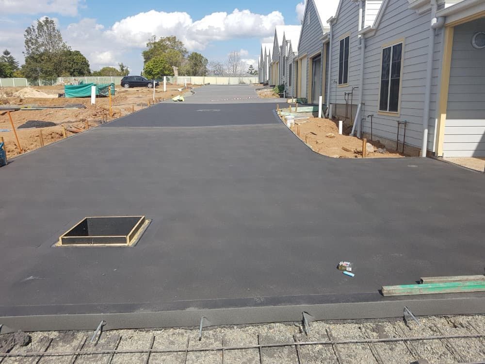 Newly Poured Concrete Driveway with Houses and A Sunny Sky — Coastcrete Concrete Specialist in Taylors Beach, NSW