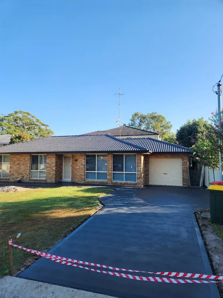 New concrete driveway in front of suburban brick home — Coastcrete Concrete Specialist in Taylors Beach, NSW — Coastcrete Concrete Specialist in Taylors Beach, NSW