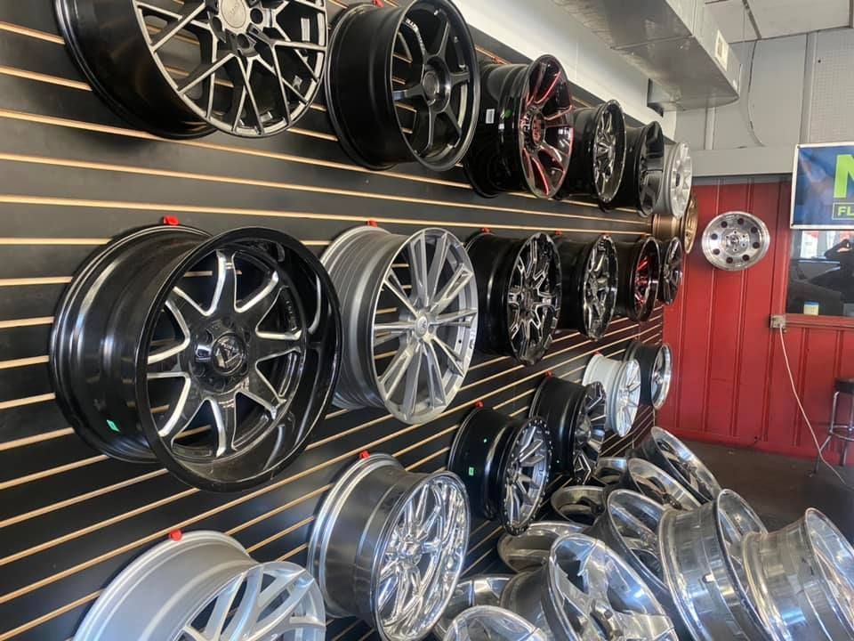 A row of wheels are lined up on a wall in a store.