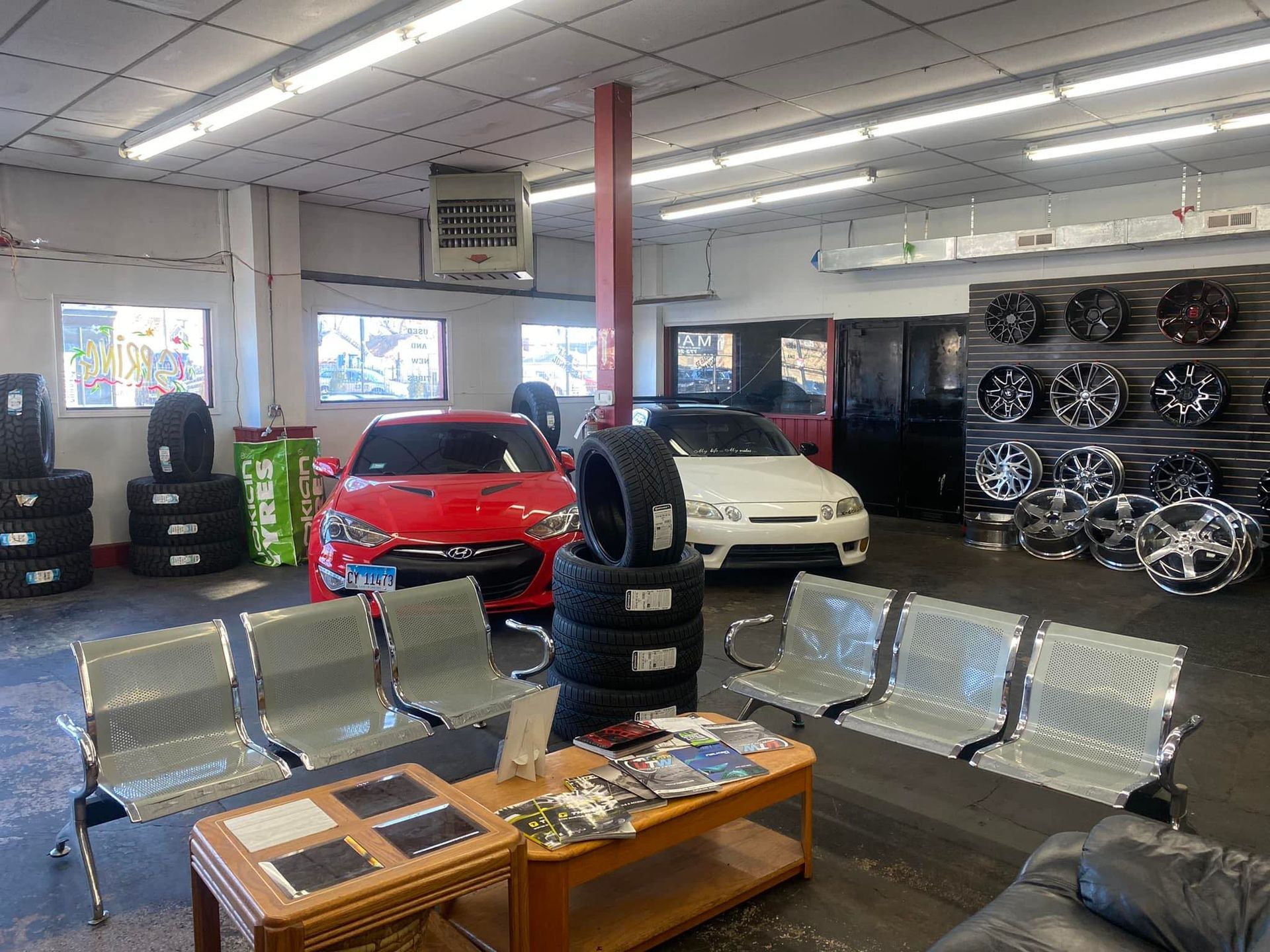 A car is parked in a garage next to a stack of tires.