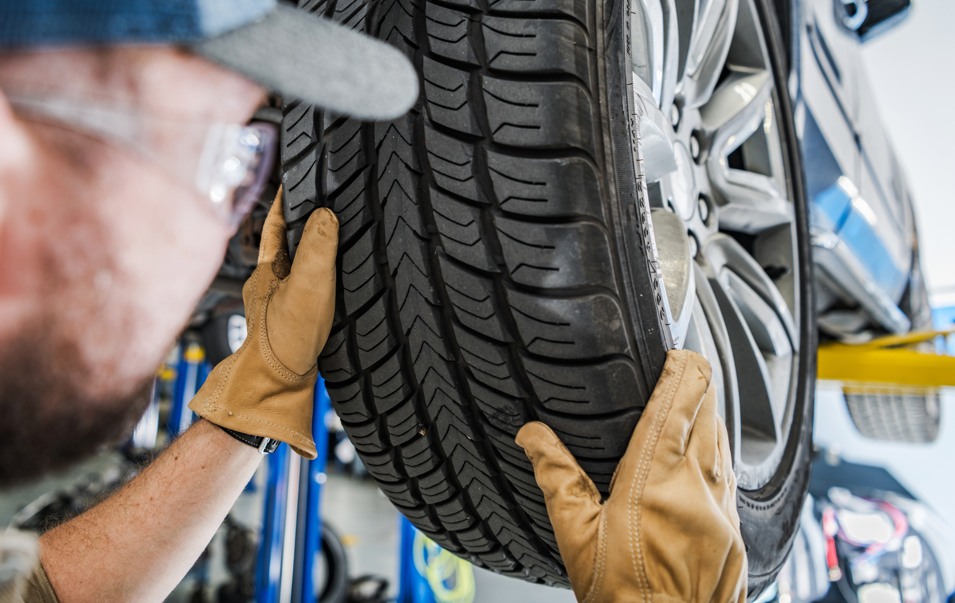 A man is holding a tire in his hands in a garage.